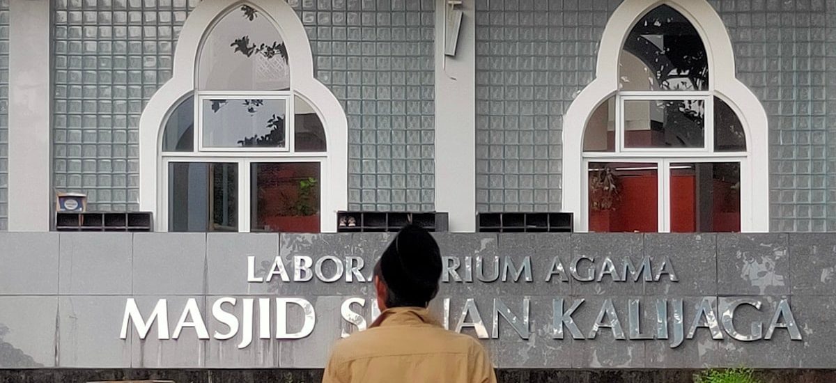 Man in front of a building with arabic writing.