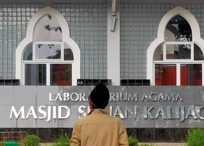 Man in front of a building with arabic writing.